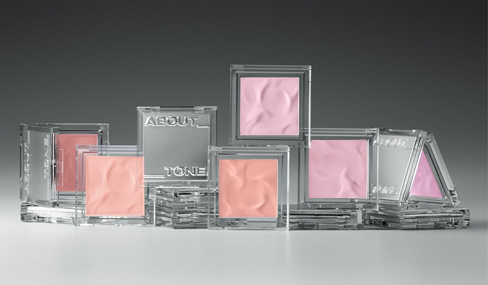Assorted pink and peach-toned blushes in clear cases, displayed on a reflective surface