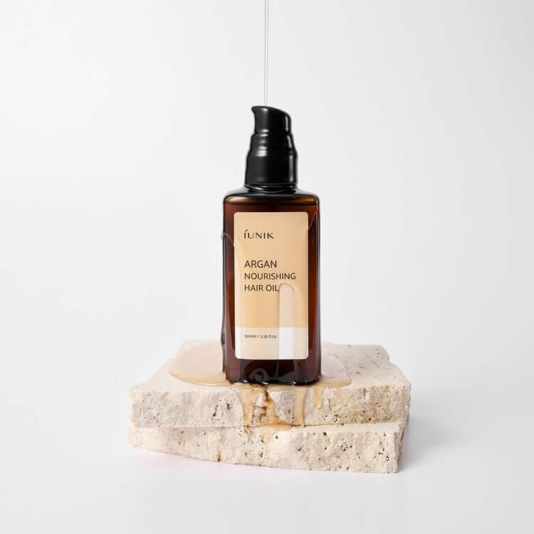 iUNIK Argan Nourishing Hair Oil 100ml bottle on a stone base for hair care
