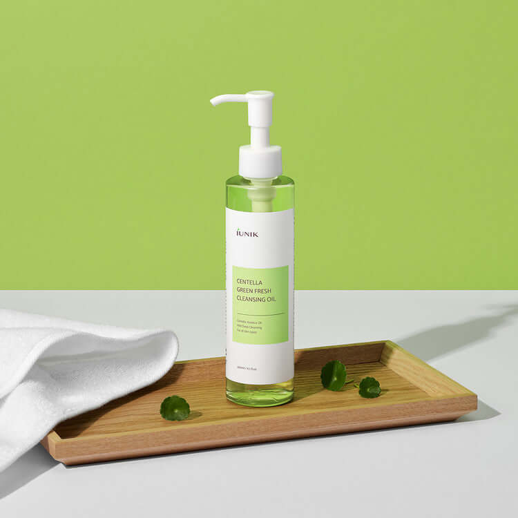 iUNIK Centella Green Fresh Cleansing Oil 200ml bottle on a wooden tray with green background.